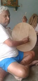 Man playing traditional drum indoors.