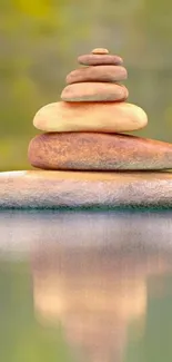 A tranquil stack of stones with a water reflection set against a soft green backdrop.