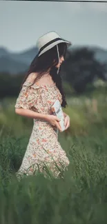 Girl in floral dress walking in a lush green meadow with a summer hat.