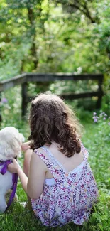 Person and dog sitting on a green forest path.