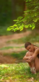 A peaceful scene with a person sitting under a tree in a lush green forest.