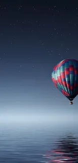 Hot air balloon under a starry sky, reflected on a calm sea at night.