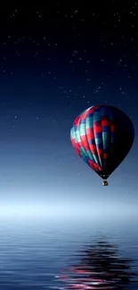 Beautiful hot air balloon against a starry night sky reflecting in calm sea.