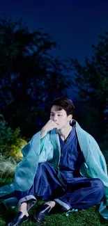 Person sitting in blue attire under the night sky.