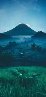 Mountain landscape at night with starry sky and glowing peak.