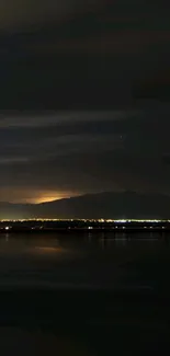 Serene nighttime mountain view with city lights in the distance.