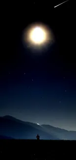 Bright moon in a night sky over silhouetted mountains.