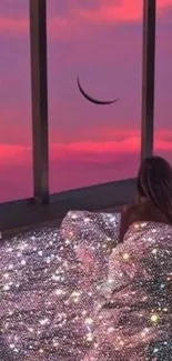 Woman wrapped in starry blanket gazing at crescent moon through glass window at sunset.