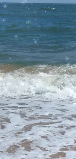 Serene ocean waves meeting a sandy beach under a clear blue sky.