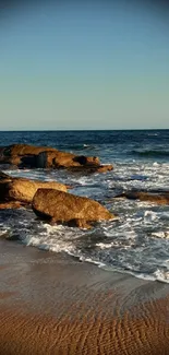 Serene ocean beach with waves and rocks in the sunset.