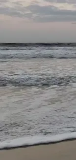 Calming ocean waves on a sandy beach at sunset.