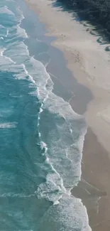 Aerial view of ocean waves gently crashing on a sandy beach.