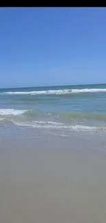 Serene beach with ocean waves under a clear blue sky.