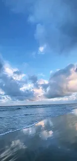 Serene ocean beach with clouds and blue sky reflecting on the water.