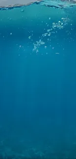 A tranquil blue ocean wallpaper with underwater bubbles.