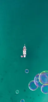 A yacht drifts on turquoise ocean water with colorful floating bubbles.