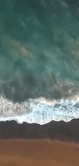 Aerial view of turquoise waves gently meeting sandy beach.