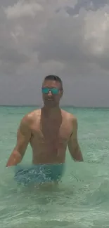 Man enjoying serene turquoise ocean under cloudy sky.