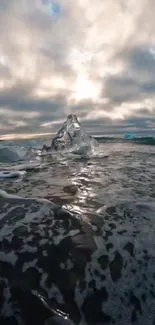 Serene ocean with iceberg under cloudy sky.