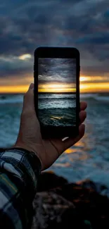 Phone displaying ocean sunset with dark sky