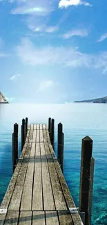 Serene view of a pier extending into a vibrant blue ocean under a clear sky.