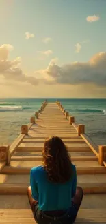 Woman sits on pier overlooking calm ocean and sunset under cloudy sky.