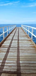 A serene wooden pier leading into the ocean under a blue sky.