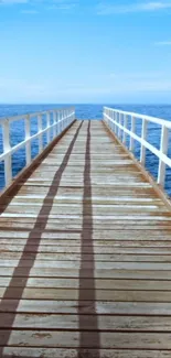 Wooden pier stretching into a tranquil blue ocean under a clear sky.