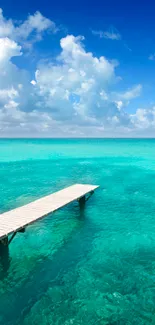 A tranquil view of a pier over turquoise ocean waters under a clear blue sky.