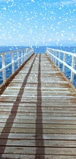 Tranquil ocean pier with snowfall and blue sky.