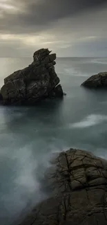 Serene ocean view with rocky formations under a cloudy sky.