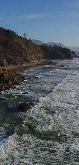 A scenic view of the ocean shore with waves and distant mountains.