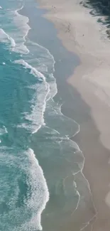 A serene aerial view of ocean waves meeting a sandy shore with blue water.