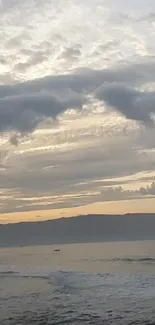 Serene ocean view at sunset with clouds and waves.