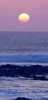 Serene sunset over ocean with purple sky and gentle waves.