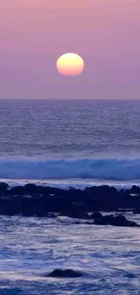 Beautiful sunset over ocean with pink and purple hues, waves gently rolling.