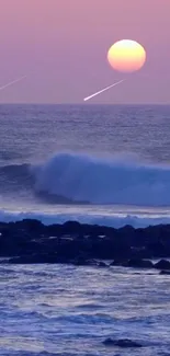 Pink sunset over ocean with gentle waves and rocks.