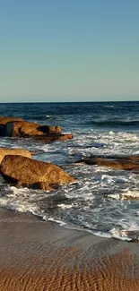 Serene ocean sunset with waves crashing on rocky shore.