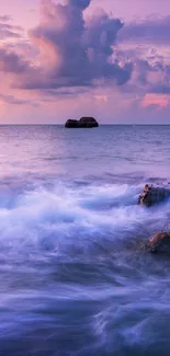 Purple sunset over ocean waves and rocks.