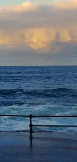 Tranquil ocean view with sunset clouds reflecting over the blue sea.