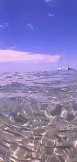 A serene ocean view with clear blue waters and a distant sailboat under a vibrant sky.