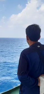 Man gazing at serene ocean under a clear sky.