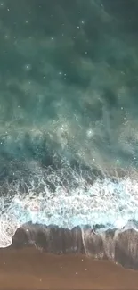 Aerial view of a serene ocean wave crashing on the sandy beach.