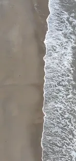 Aerial view of ocean waves meeting sandy shore.