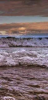 Majestic ocean waves under a moody sky at sunset.