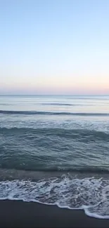 Peaceful ocean waves and sunrise sky over a sandy beach.