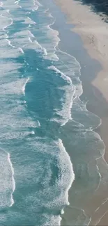 Aerial view of ocean waves gently hitting a sandy shoreline.