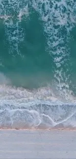 Calming teal ocean waves crash onto a sandy beach.