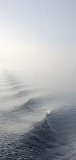 Serene ocean waves under a misty sky.