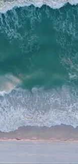 Aerial view of teal ocean waves gently hitting the sandy shore.